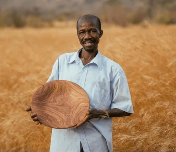 artisan holding wooden bowl in a field