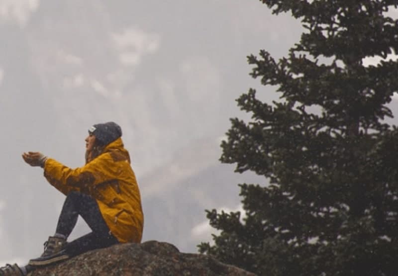 women wearing yellow jacket sitting on top of a mountain