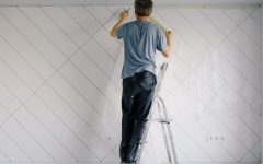 Painter standing on a ladder facing the wall