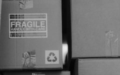 Grayscale picture of stacked boxes with one labeled ‘fragile’