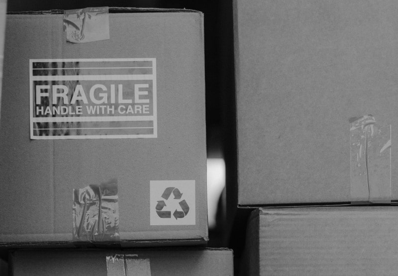 Grayscale picture of stacked boxes with one labeled ‘fragile’